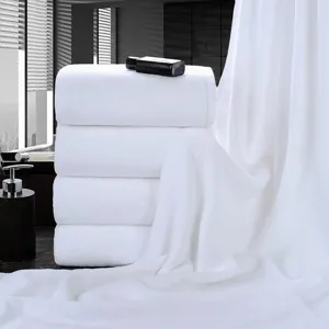 Premium white cotton hotel bath towels stacked in a minimalist bathroom setting