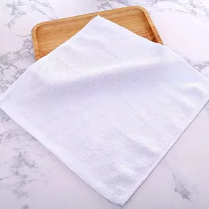 Detail view of a white cotton square towel on a wooden tray with marble background