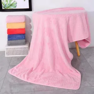 Vista detallada de una toalla de baño gruesa de vellón de coral rosa, suave y muy absorbente