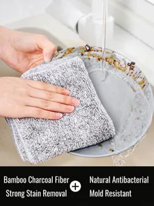 Macro view of absorbent bamboo charcoal fiber dishcloth cleaning a greasy plate