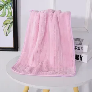 Vista detallada de la suave textura de una toalla de forro polar coral rosa en una mesa.