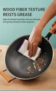 Primo piano di un panno in fibra di legno che pulisce il grasso da un wok strutturato