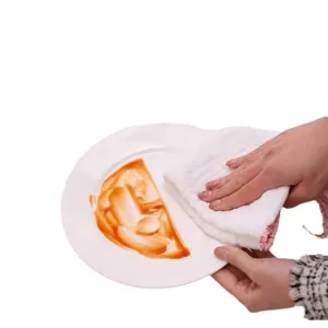 Strofinaccio in cotone spesso che rimuove macchie d'olio da un piatto in ceramica