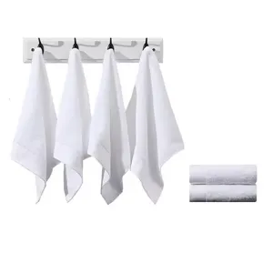 Set witte katoenen vierkante handdoeken opgehangen aan minimalistische wandhaken