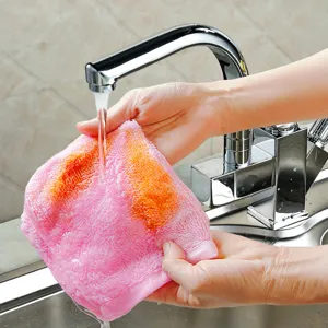 Detail view of hands rinsing a pink and orange thick wood fiber dishcloth under running water