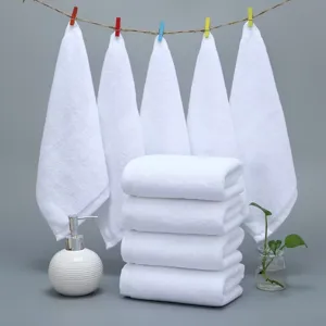 Stack of soft white cotton square towels displayed in a clean bathroom setting with plants.