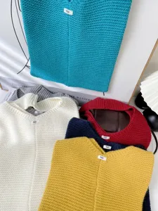 Variety of colorful knitted tote bags in teal, cream, mustard, and red tones.