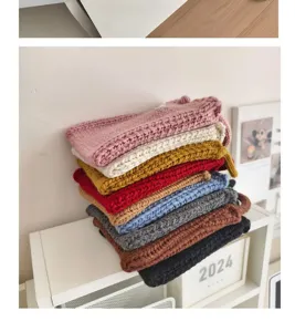 Stack of colorful handmade knitted crossbody bags in soft candy tones for winter