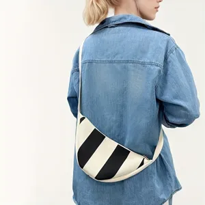 Back view of a model wearing a black and white striped woven crossbody crescent bag