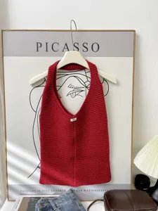 Detail of a red knitted large capacity tote bag hanging in a chic indoor setting