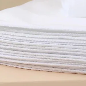 Close-up of stacked white thickened disposable hand towels showing textured weave