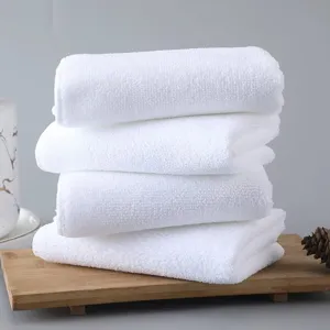 Close-up of four soft white absorbent microfiber washcloths stacked on a rustic wood tray