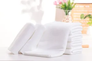 Detailed macro view of soft white disposable hotel towels stacked neatly on a white table