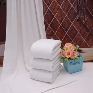 Close-up of white thickened absorbent cotton bath towels stacked on a white surface