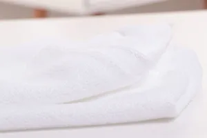 Detailed close-up of white disposable hotel towel showing soft absorbent fabric texture