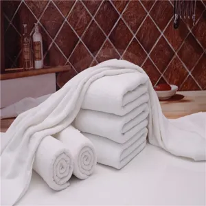 Close-up of thick white cotton bath towels showing soft texture in a luxury hotel bathroom