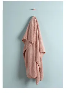 Vista dettagliata di un asciugamano da bagno rosa con trama a nido d'ape appeso a un gancio
