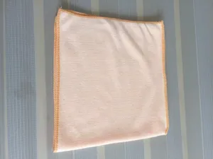 Detail view of a soft peach-colored microfiber towel with reinforced overlocked edges