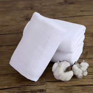 Primo piano di asciugamani in cotone bianco piegati con fiori di cotone su legno
