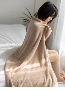 Morbido asciugamano da bagno a nido d'ape sulle spalle di una donna in una camera luminosa.