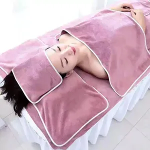 Detailansicht eines hochwertigen rosa Mikrofaser-Spa-Handtuchsets auf einer Massageliege