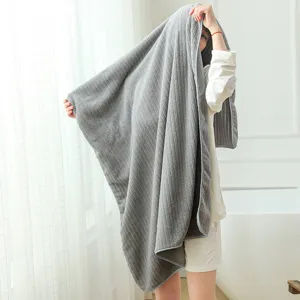 Soft grey striped coral fleece bath towel held by a woman in a cozy home setting