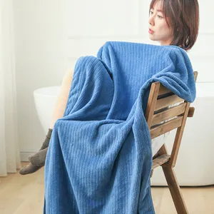 Soft blue striped coral fleece bath towel draped over a wooden chair in a bright room