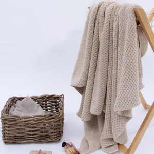 Toalla de baño grande de nido de abeja beige colgada en un tendedero de madera para casa