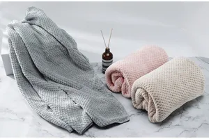 Dettaglio macro di tre asciugamani da bagno a nido d'ape in grigio, rosa e beige.