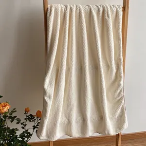 Grande asciugamano da bagno crema assorbente a nido d'ape su una scala di legno.