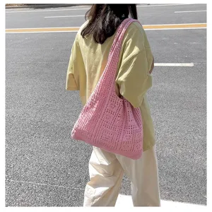 Modèle portant un sac à bandoulière rose vintage en maille ajourée dehors