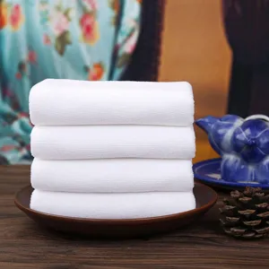 Close-up of four stacked white absorbent microfiber washcloths on a ceramic plate.