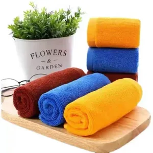 Set of colorful absorbent microfiber square towels rolled on wooden board