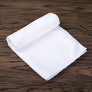 Close-up of a soft white absorbent microfiber square towel on a wooden surface.