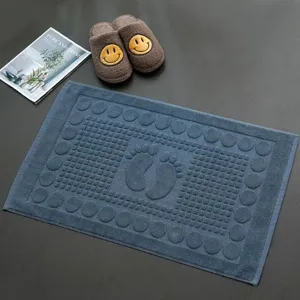 Premium blue cotton absorbent bath mat with embossed foot pattern for luxury bathroom use