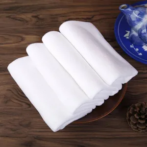 Soft absorbent white towels folded on wooden table with elegant tea set decor