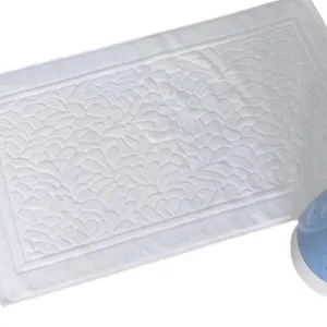 Thick white cotton bath mat featuring a textured leaf pattern for hotel style bathroom