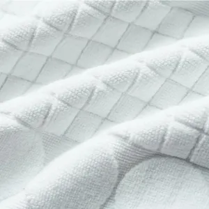 Macro shot of white pure cotton hotel floor mat with embossed grid pattern and soft texture
