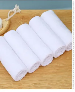 Detailweergave van vijf gerolde witte puur katoenen vierkante washandjes op houten tafel