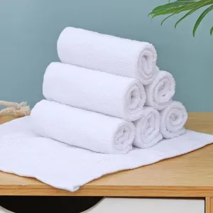 Gedetailleerd overzicht van zachte witte katoenen vierkante handdoeken op houten tafel