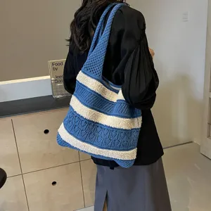 Lifestyle view of a blue and white striped knit shoulder bag in a modern indoor setting