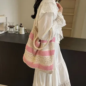 Pink and cream striped knit crochet tote bag carried by a model in a lifestyle setting