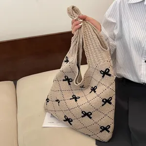 Close-up of knitted tote bag featuring black bow patterns and diamond grid texture