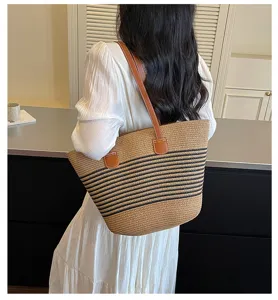 Rear view of a model carrying a large striped straw woven tote bag in a stylish setting