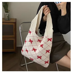 Detailed view of white knitted tote bag with red bow pattern and wide handles