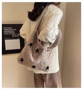 Beige star-patterned knitted tote bag shown on model wearing white cable sweater