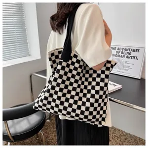 Large capacity knitted checkerboard tote bag carried by a model in a stylish indoor setting