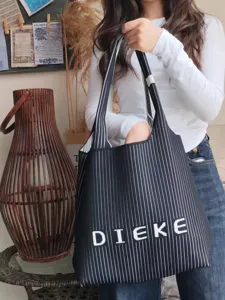 Close-up detail showing the texture of a black and white striped fly-knit tote bag