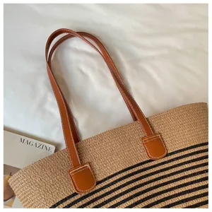 Detailed view showing the brown leather shoulder straps on a striped straw woven tote bag