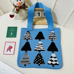 Knitted blue tote bag with festive Christmas tree pattern displayed in a holiday scene
